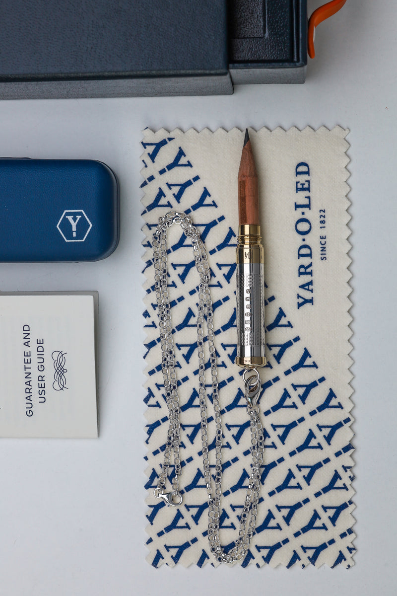 Yard O'LED product with necklace on branded cloth, close-up on white surface